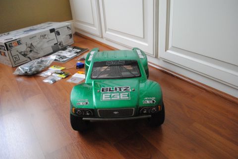 1986 Ford Bronco - Green RC truck and its parts laid out on a wooden floor next to a box.