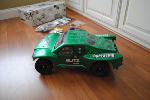 1986 Ford Bronco - A green remote control truck sits on a wooden floor near its packaging and parts.