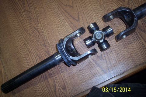 1973 Ford F-250 - A disassembled universal joint and yoke assembly is shown on a wooden surface, with a date stamp in the corner.