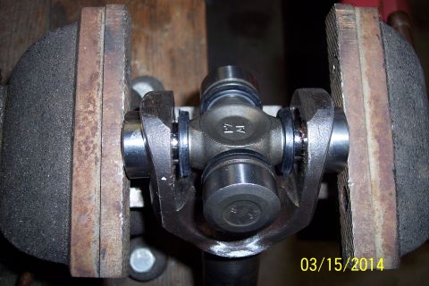 1973 Ford F-250 - A universal joint is clamped in a vise, revealing mechanical details and some surface wear.