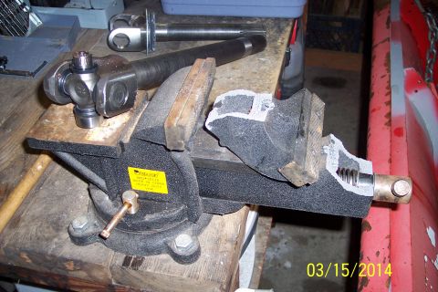 1973 Ford F-250 - A driveshaft universal joint is secured in a vise, with a second driveshaft visible behind it, suggesting a repair or assembly process.