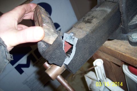 1973 Ford F-250 - A metal part is held in a vise, showing a cut-out with red material and screw threads visible.