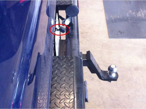 1982 Ford Bronco - Close-up of a blue vehicle's rear bumper, showing a trailer hitch and a sensor circled in red.