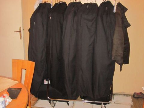1991 Ford Crown Victoria - A garment rack is filled with multiple black coats and one brown jacket hanging on hangers.