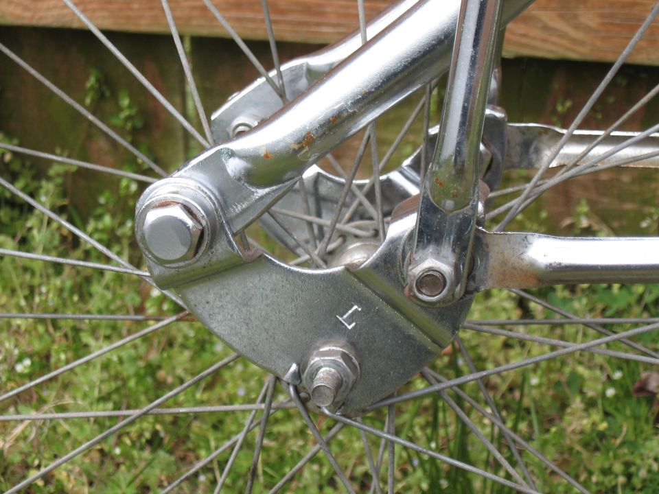 Chrome bicycle fork with a metal bracket marked 'L' and a spoked wheel