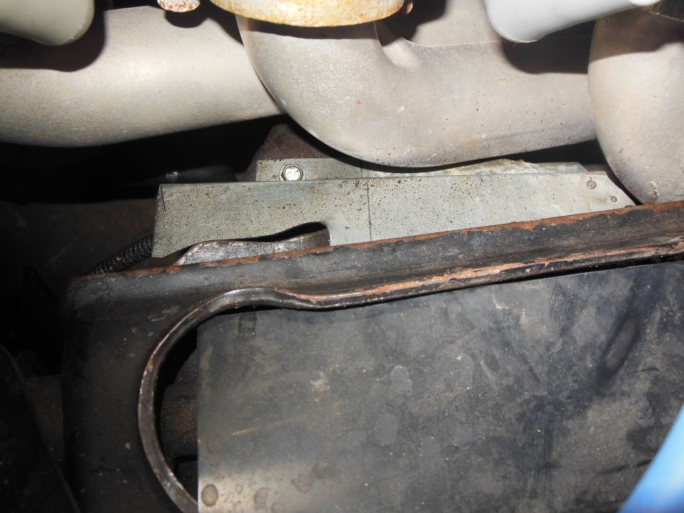 Coated exhaust header tubes above a notched metal heat shield in an engine bay