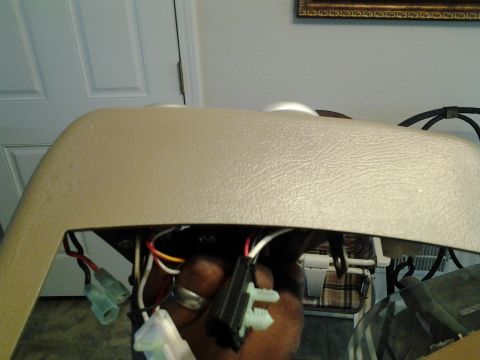 2004 Ford Crown Victoria - Exposed wiring and connectors are visible beneath a tan dashboard trim piece in a vehicle.