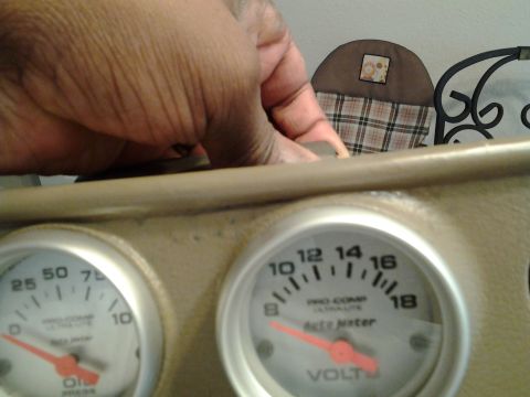 2004 Ford Crown Victoria - A hand is shown near two aftermarket gauges, an oil pressure gauge and a voltmeter, mounted on a dashboard.