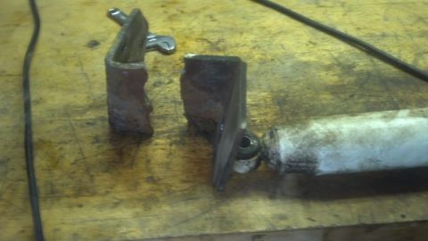 1995 Ford Bronco - A broken shock absorber mount lies on a wooden surface, with a wrench nearby.