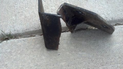 1995 Ford Bronco - These rusted metal brackets appear to be parts from a vehicle, possibly related to suspension or mounting.