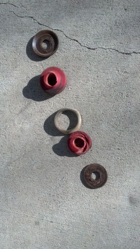 1995 Ford Bronco - Worn shock bushings and washers are laid out on a concrete surface.