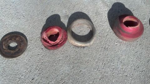 1995 Ford Bronco - Several deteriorated rubber suspension bushings are laid out on a concrete surface, showing signs of wear and tear.