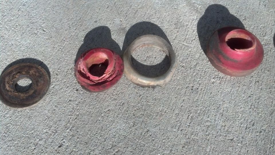 Worn red and clear rubber suspension bushings on concrete