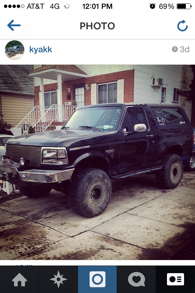 Black 1995 Ford Bronco with large tires parked in front of a house