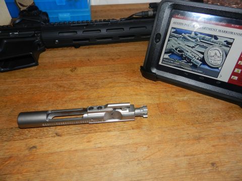 1996 Ford Bronco - A firearm bolt and rifle are displayed on a wooden table next to a tablet showing a webpage about marksmanship.