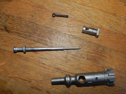1996 Ford Bronco - Several disassembled firearm components are arranged on a wooden table, including a bolt and firing pin.