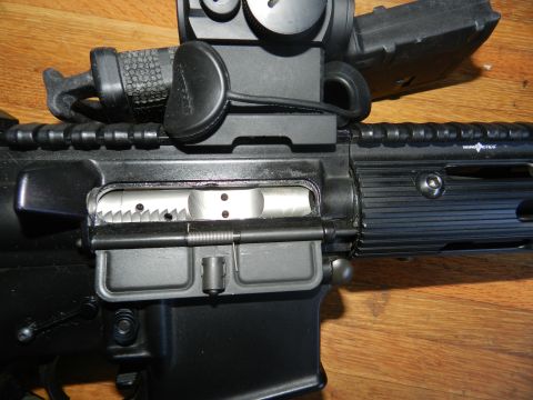 1996 Ford Bronco - Close-up of an AR-15 rifle's upper receiver assembly, including the charging handle and optic.