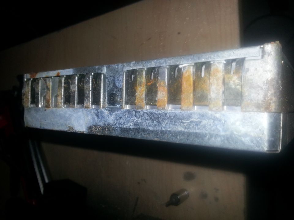 Rusted metal component with vertical fins, possibly an old heat sink or radiator part