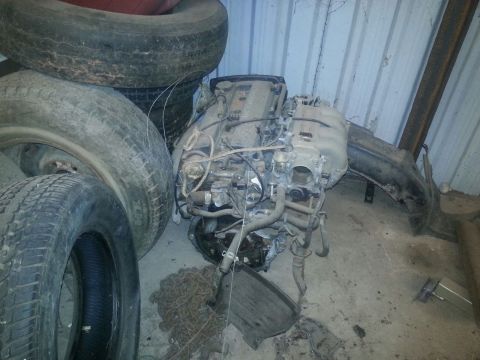 1991 Ford Festiva - Engine and tires are stored together, likely for parts or repair.