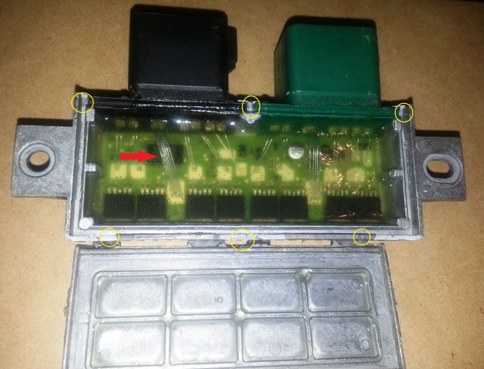 Opened vehicle control module showing gel-covered circuit board, with tabs circled in yellow and a red arrow marking a chip