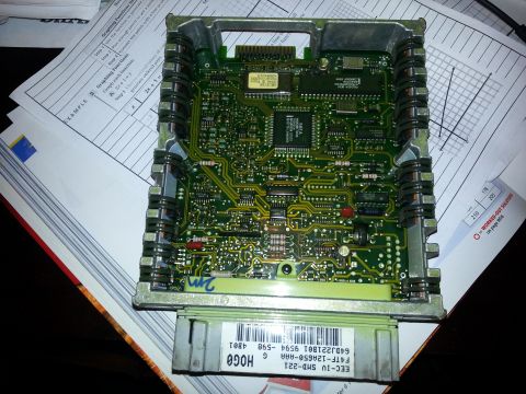 1994 Ford Bronco - An electronic control unit with a complex circuit board is shown, resting on papers with diagrams.