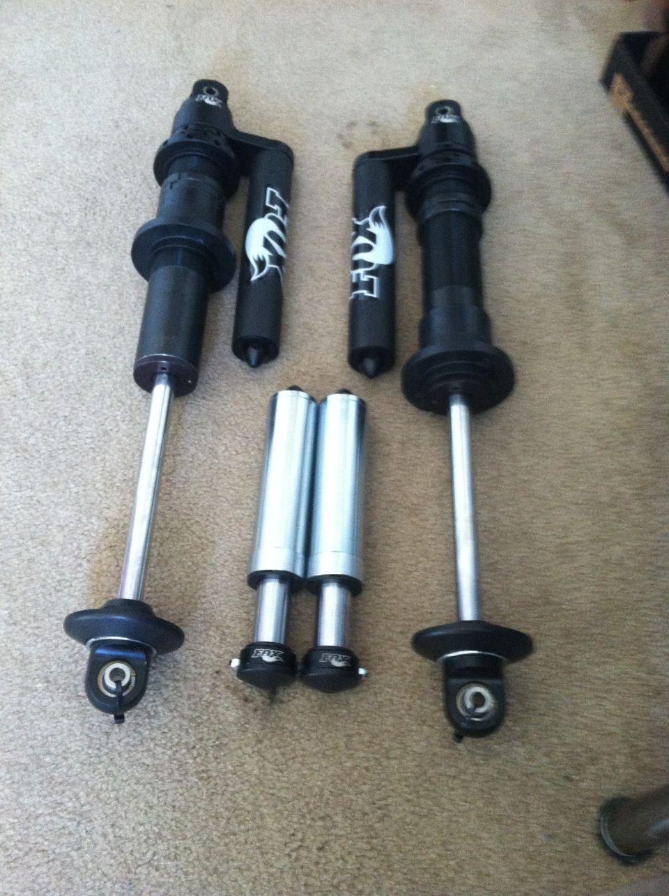 Two Fox shocks with reservoirs and two separate reservoirs on a carpeted surface