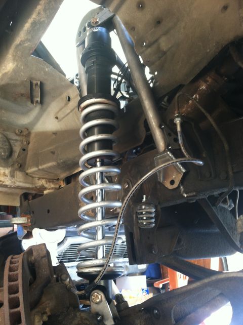 1977 Ford F-350 - Close-up view of a custom front coilover suspension system, likely for an off-road or performance vehicle.