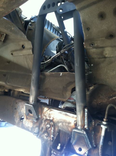 1977 Ford F-350 - Custom front suspension components are welded onto a rusty frame, with a radiator visible in the background.