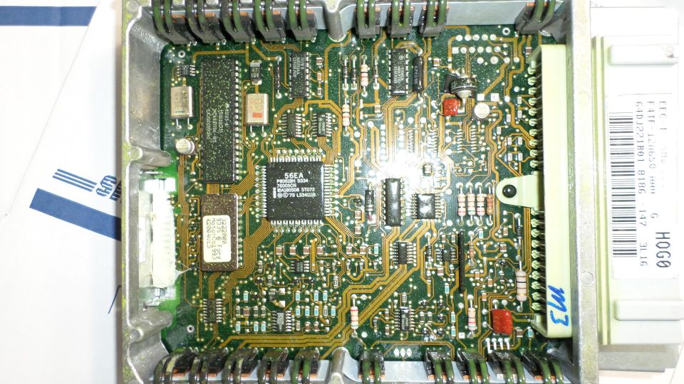 Engine control unit circuit board with visible chips and connectors, some text labels present