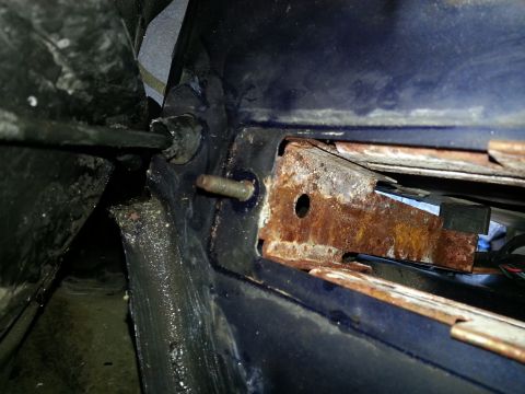 1994 Ford Bronco - This image shows a close-up of a rusted metal bracket and a cable, likely from a vehicle's interior or machinery's internal components.