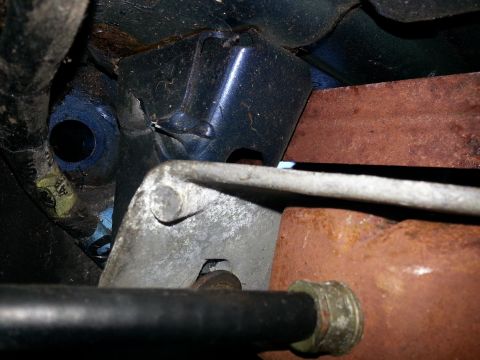 1994 Ford Bronco - Undercarriage view shows a rusty metal bracket and a black pipe, likely part of the exhaust or suspension system.
