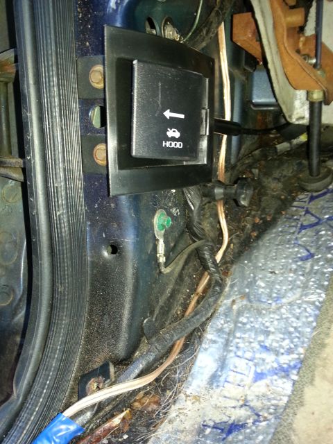 1994 Ford Bronco - Close-up of a car's interior showing the hood release lever mechanism and wiring.