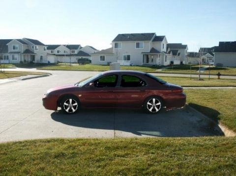 1998 Mercury Sable - A red 1998 Mercury Sable sedan is seen from the side in a residential neighborhood.