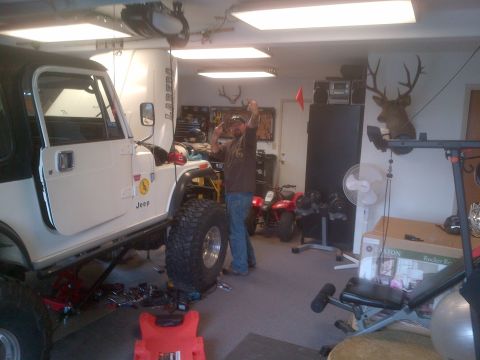 1985 Jeep CJ7 - White 1985 Jeep CJ7 in a garage, modified with a lifted suspension and large off-road tires.