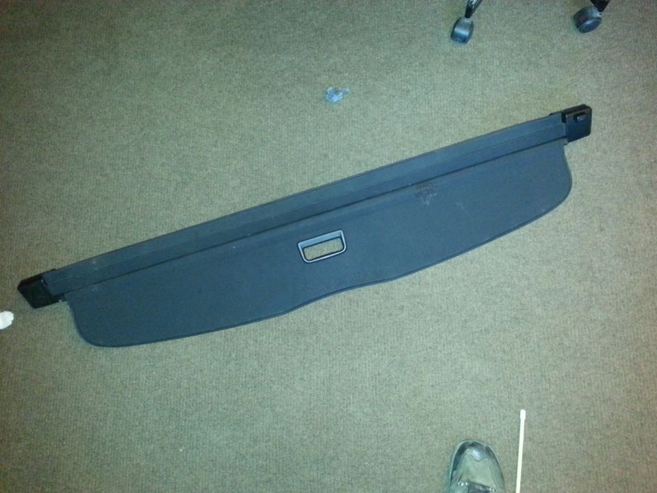 Black retractable cargo cover with a gray handle