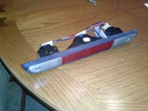 1995 Ford Bronco - A car tail light assembly with visible wiring rests on a wooden surface.