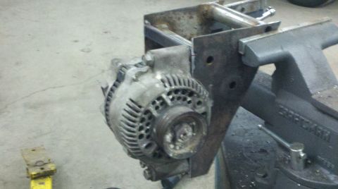 1989 Ford F-150 - An automotive alternator is held in a vise, mounted to a metal frame.