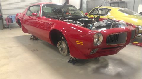 1972 Pontiac Trans Am - Red 1970 Pontiac Firebird in a garage, missing wheels and undergoing maintenance.