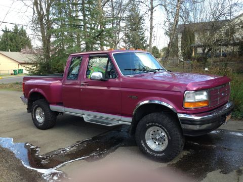 1992 Ford F-150 - Freshly washed burgundy OBS Ford extended-cab Flareside pickup shot from the passenger-side 3/4 front on a wet driveway, soap suds still ru…