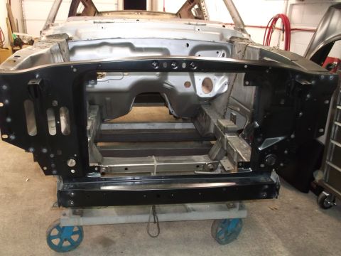 1967 Ford Mustang - The front end of a car is disassembled and mounted on a dolly, showing the chassis and internal structure.