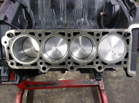 2004 Ford Crown Victoria - Close-up view of an engine block showing four cylinders and pistons with visible 'JE' markings.