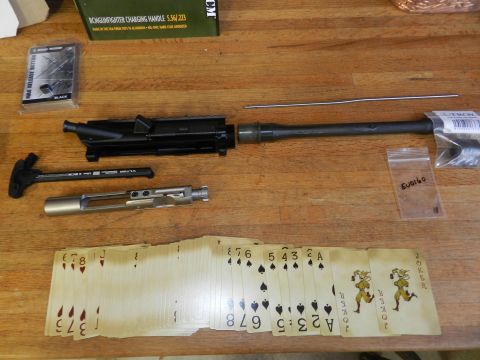 1996 Ford Bronco - AR-15 components and a fanned deck of playing cards are arranged on a wooden table.