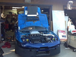 1995 Ford Probe - A blue 1995 Ford Probe is parked in a garage with its hood open, revealing the engine.