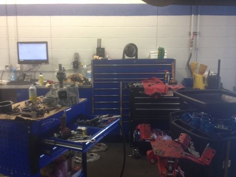 1995 Ford Probe - A cluttered auto repair bay shows various tools, parts, and equipment, including a computer displaying information.