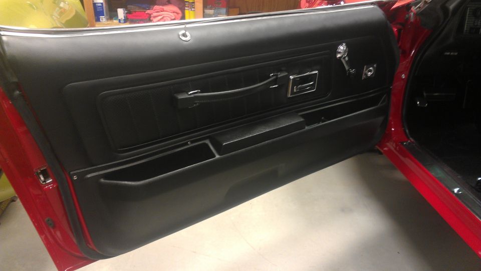 Red car interior with black door panel, chrome handle, and storage compartments