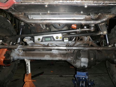 1961 International Scout 800 - Close-up of a vehicle's steering and suspension system, showing various metal components and a digital level.