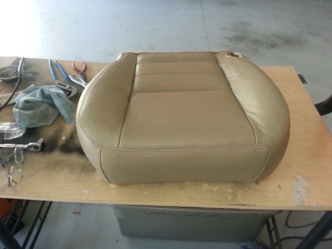 1994 Ford Bronco - A tan leather car seat is on a workbench with various tools scattered around it.