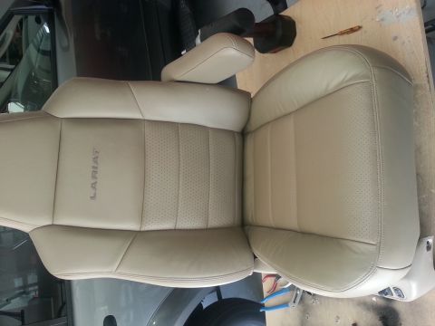 1994 Ford Bronco - A tan leather driver's seat, identified as Lariat, is shown with perforated inserts and a prominent armrest.