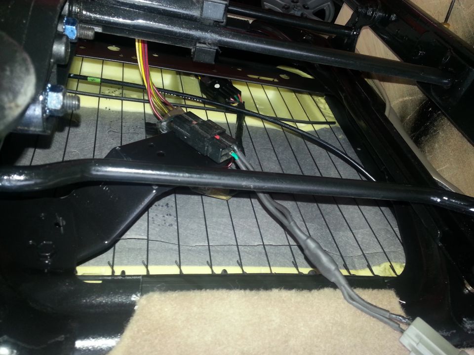 Close-up of vehicle seat frame with exposed wiring and connectors