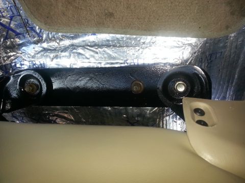 1994 Ford Bronco - Close-up of a seat mounting bracket, partially covered by sound deadening material.
